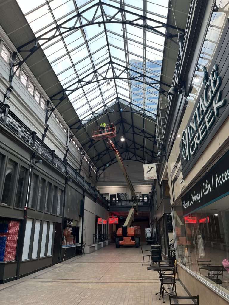 Boom lift reaching a glass atrium ceiling for electrical installation