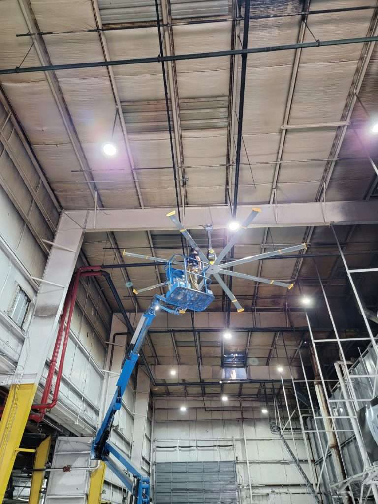 Boom lift installing a ceiling fan in a high bay facility