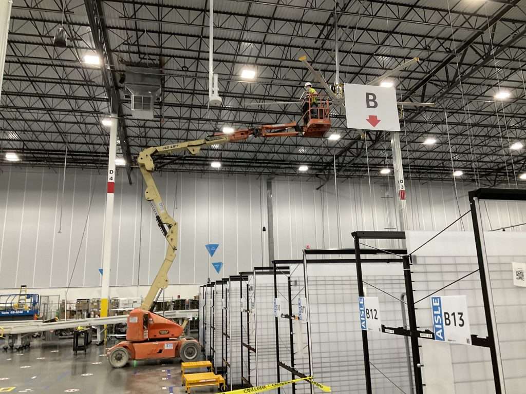 Electrician on a boom lift working at the ceiling of a fulfillment center