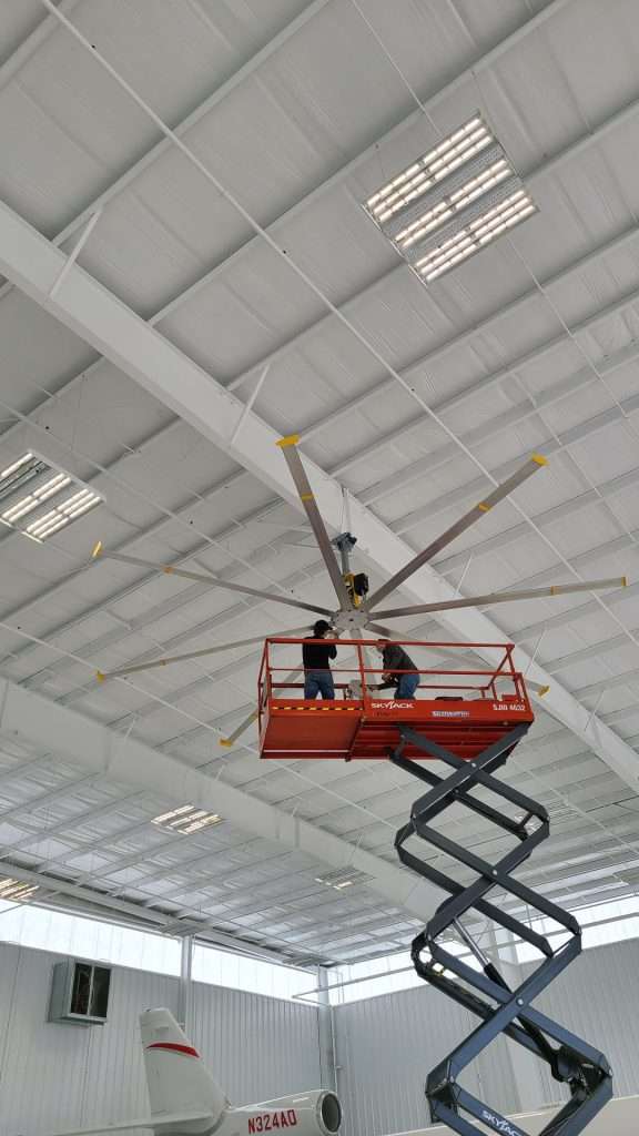 HVLS fan installation from a scissor lift inside an aircraft hangar