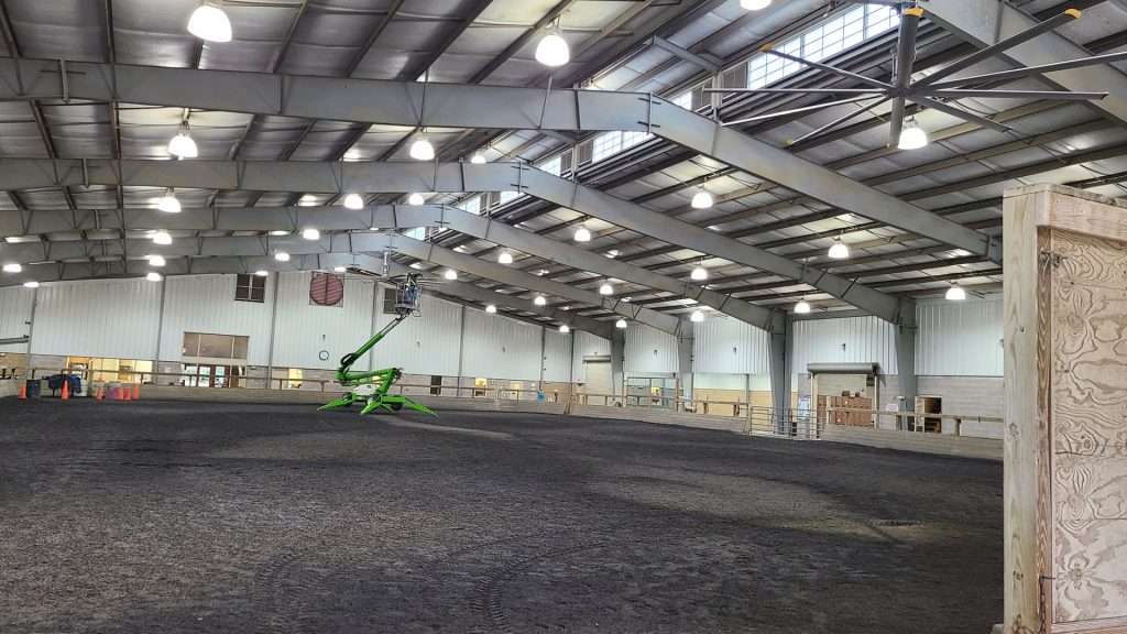 Boom lift installing ceiling fans in a large indoor arena