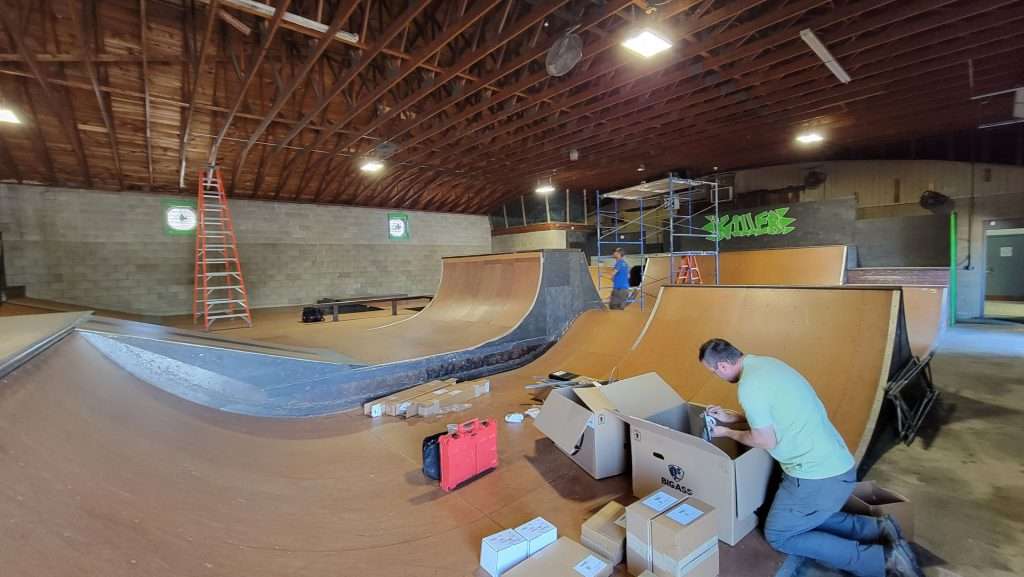 Technician unboxing fan equipment before installation at an indoor skatepark