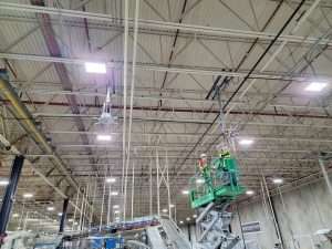 Crew on a lift installing an industrial ceiling fan in a manufacturing plant
