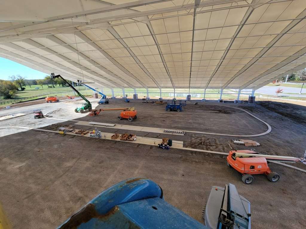 Aerial lifts inside an open-air pavilion during construction and electrical installation