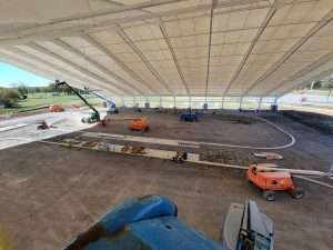 Aerial lifts inside an open-air pavilion during construction and electrical installation