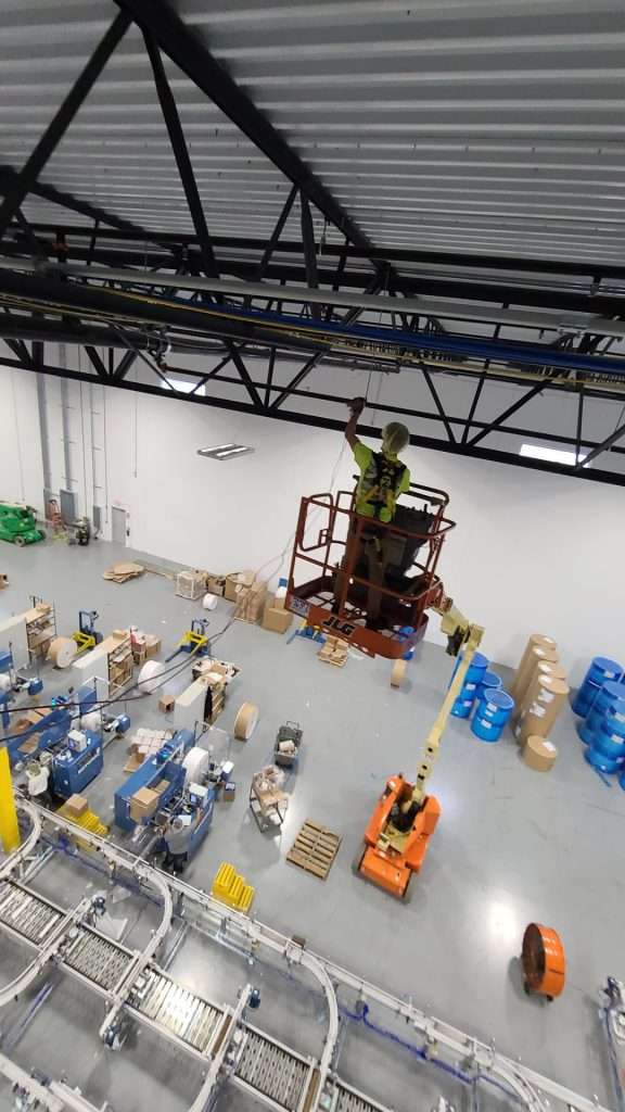 Overhead electrical installation from a lift above a distribution center floor