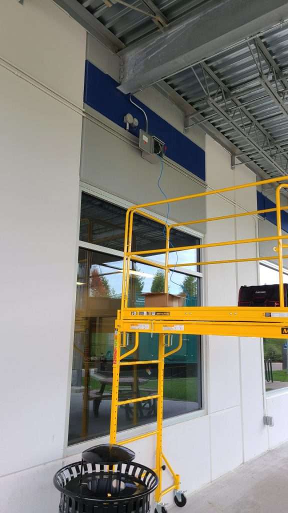 Rolling scaffold at a commercial building entrance for exterior electrical work